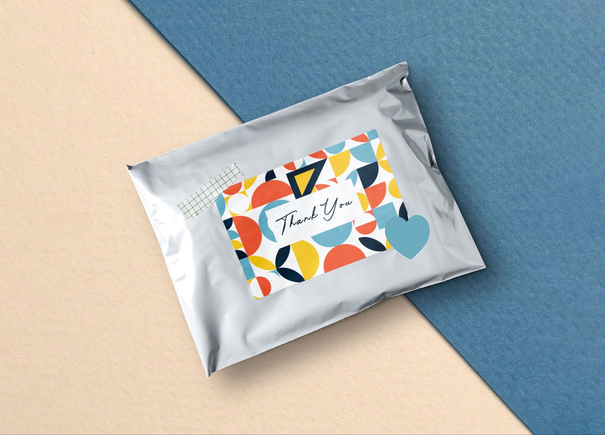 Corrugated mailer apparel packaging box with colorful geometric print, containing a folded basic shirt and a knitted maroon hoodie